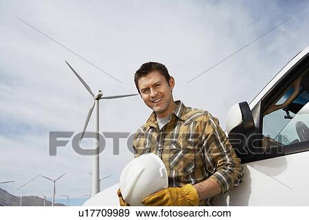Stock Photo - Engineer by car at wind farm, portrait. Fotosearch