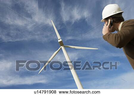 Engineer using mobile phone at wind farm View Large Photo Image Stock Photo - Engineer using mobile phone at wind farm. Fotosearch