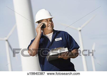 Engineer using mobile phone at wind farm View Large Photo Image Stock Photo - Engineer using mobile phone at wind farm. Fotosearch