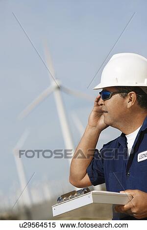 Engineer using mobile phone at wind farm View Large Photo Image Stock Photography - Engineer using mobile phone at wind farm. Fotosearch