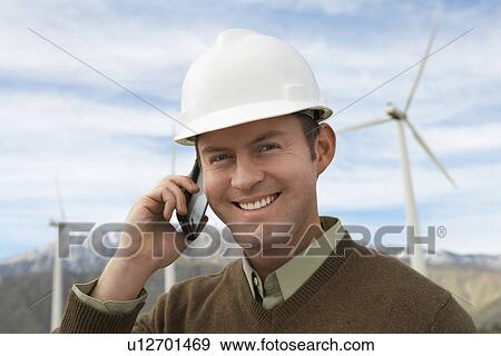 Engineer using mobile phone at wind farm, portrait View Large Photo Image Stock Photo - Engineer using mobile phone at wind farm, portrait. Fotosearch
