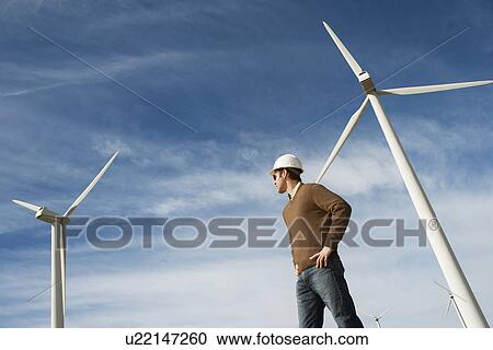 Stock Image - Engineer wearing hardhat at wind farm. Fotosearch