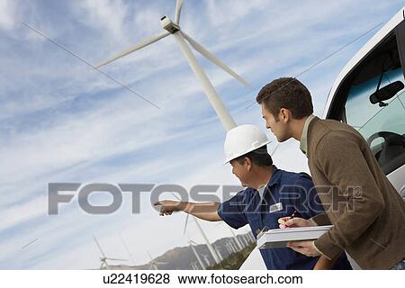 Engineers examining wind turbines by car at wind farm View Large Photo Image Stock Photo - Engineers examining wind turbines by car at wind farm. Fotosearch