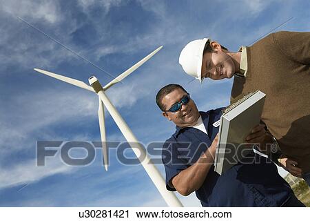 Stock Image - Engineers working at wind farm. Fotosearch