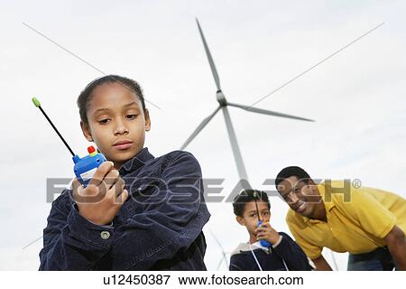 Father and children (7-9) playing with walky-talkies at wind farm View Large Photo Image Stock Photo - Father and children (7-9) playing with walky-talkies at wind farm. Fotosearch