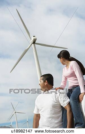 Stock Photo - Father and daughter (7-9) near wind turbines at wind farm. Fotosearch