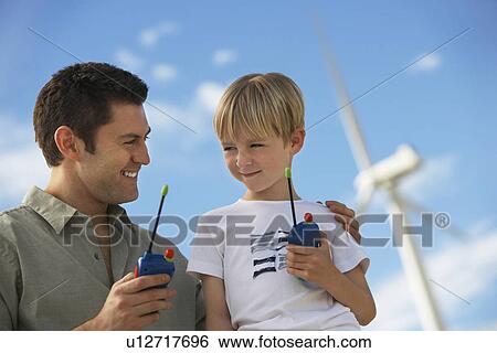 Father and son (7-9) holding toy walky-talkies at wind farm View Large Photo Image Stock Photograph - Father and son (7-9) holding toy walky-talkies at wind farm. Fotosearch