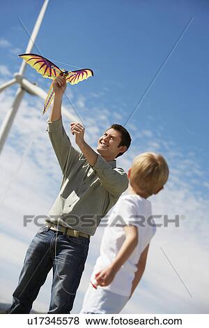 Father and son (7-9) playing with kite at wind farm View Large Photo Image Stock Photo - Father and son (7-9) playing with kite at wind farm. Fotosearch