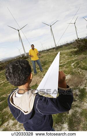 Father and son (7-9) playing with paper plane at wind farm View Large Photo Image Stock Photo - Father and son (7-9) playing with paper plane at wind farm. Fotosearch