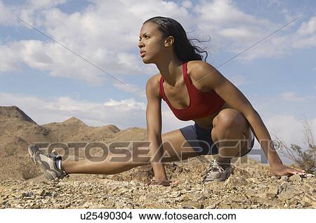 Picture - Female jogger stretching in mountains. Fotosearch