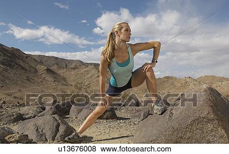 Stock Photo - Female jogger stretching in mountains. Fotosearch