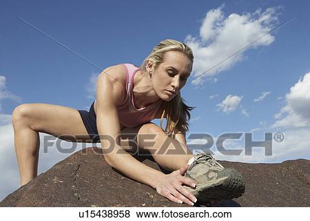 Stock Photo - Female jogger stretching on rock. Fotosearch