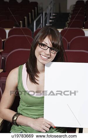 Female student holding blank board in lecture theatre, portrait View Large Photo Image Stock Photo - Female student holding blank board in lecture theatre, portrait. Fotosearch