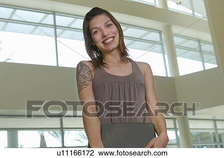 Stock Image - Female student smiling, indoors, portrait. Fotosearch