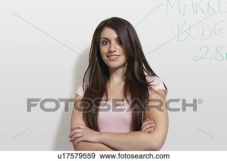 Stock Photo - Female student standing by white board, portrait. Fotosearch