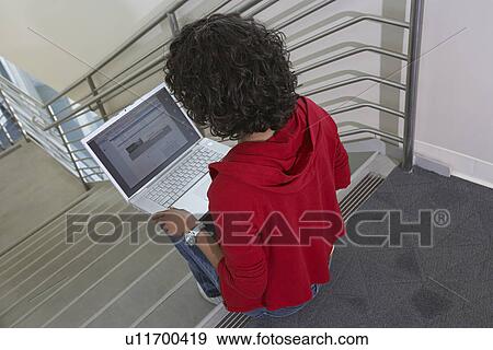 Stock Photo - Female student using laptop on stairs. Fotosearch