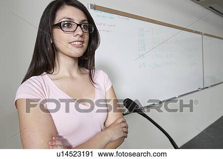 Stock Image - Female student using microphone indoors. Fotosearch