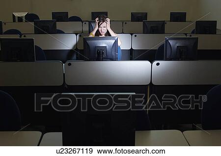 Stock Photo - Female student with head in hands in computer classroom. Fotosearch