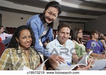 Stock Photo - Female teacher assisting students in class, portrait. Fotosearch