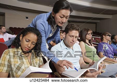 Picture - Female teacher assisting students during lesson. Fotosearch