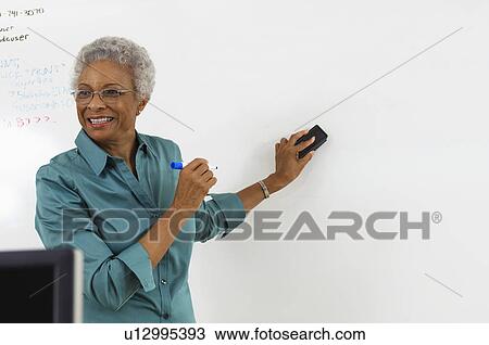 Female teacher erasing text on whiteboard in classroom View Large Photo Image Stock Image - Female teacher erasing text on whiteboard in classroom. Fotosearch