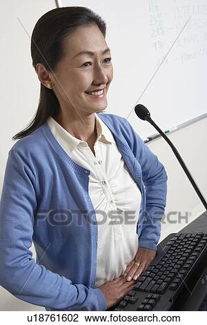 Female teacher smiling in lecture theatre View Large Photo Image Stock Image - Female teacher smiling in lecture theatre. Fotosearch