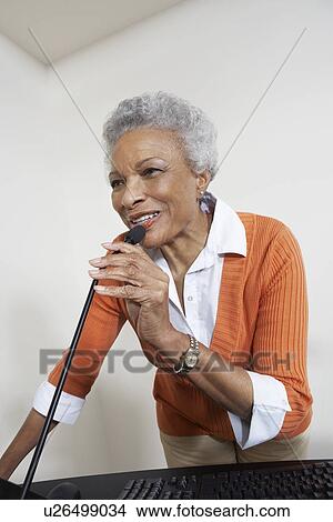Picture - Female teacher using microphone indoors. Fotosearch