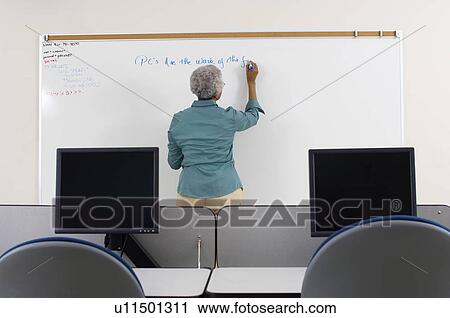 Female teacher writing on whiteboard in computer classroom View Large Photo Image Stock Image - Female teacher writing on whiteboard in computer classroom. Fotosearch