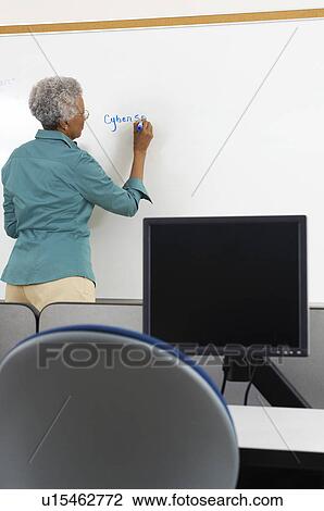 Female teacher writing on whiteboard in computer classroom View Large Photo Image Stock Image - Female teacher writing on whiteboard in computer classroom. Fotosearch