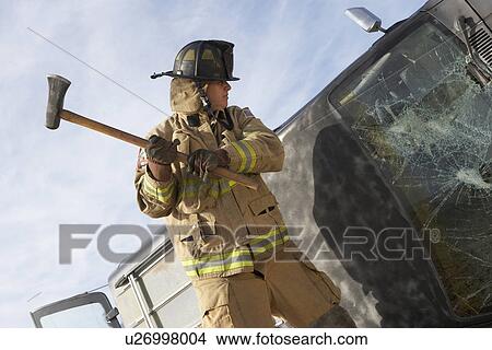 Picture - Firefighter hitting crashed car with axe. Fotosearch