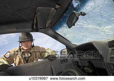Stock Photo - Firefighter looking into crashed car, view from interior. Fotosearch
