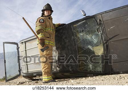 Firefighter standing by crashed car View Large Photo Image Picture - Firefighter standing by crashed car. Fotosearch