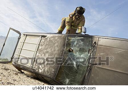 Stock Image - Firefighter trying to get into crashed car. Fotosearch