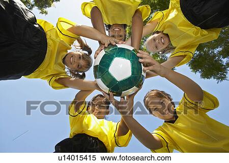 Stock Photography - Five children (7-9 years) holding soccer ball, view from below, portrait. Fotosearch