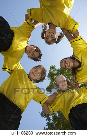Stock Photo - Five children soccer players (7-9 years) huddling, view from below, portrait. Fotosearch