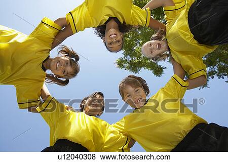 Stock Photo - Five children soccer players (7-9 years) huddling, view from below, portrait. Fotosearch