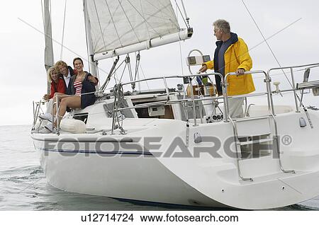 Picture - Four people on sailboat in sea. Fotosearch