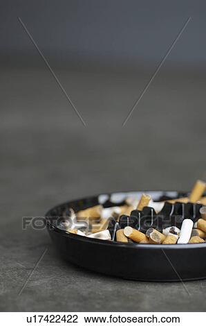 Stock Image - Full ashtray of cigarettes on table. Fotosearch