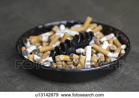 Full ashtray of cigarettes on table, close-up View Large Photo Image Stock Photo - Full ashtray of cigarettes on table, close-up. Fotosearch
