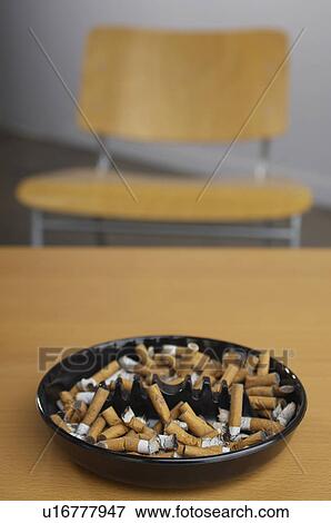 Stock Photo - Full ashtray of cigarettes on table. Fotosearch