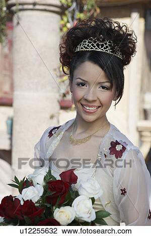 Stock Image - Girl (13-15) with bouquet at Quinceanera, portrait. Fotosearch