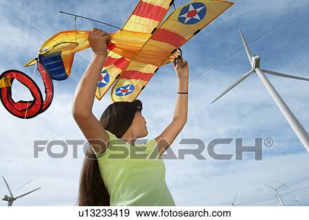 Girl (7-9) holding airplane kite at wind farm View Large Photo Image Stock Photo - Girl (7-9) holding airplane kite at wind farm. Fotosearch