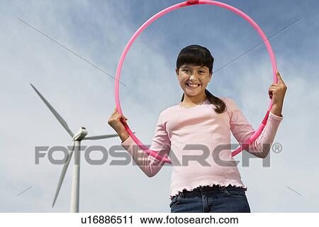 Girl (7-9) holding hula hoop at wind farm, portrait View Large Photo Image Stock Image - Girl (7-9) holding hula hoop at wind farm, portrait. Fotosearch