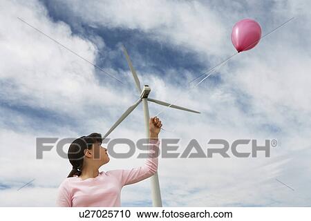 Stock Image - Girl (7-9) playing with balloon at wind farm. Fotosearch