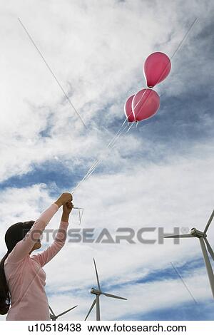Stock Photo - Girl (7-9) playing with balloons at wind farm. Fotosearch