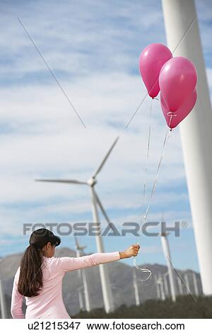 Stock Photo - Girl (7-9) playing with balloons at wind farm. Fotosearch