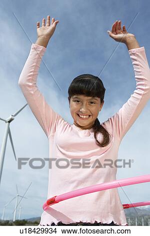 Picture - Girl (7-9) playing with hula hoop at wind farm, portrait. Fotosearch