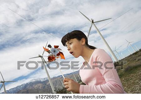 Girl (7-9) playing with toy windmill at wind farm View Large Photo Image Stock Photo - Girl (7-9) playing with toy windmill at wind farm. Fotosearch
