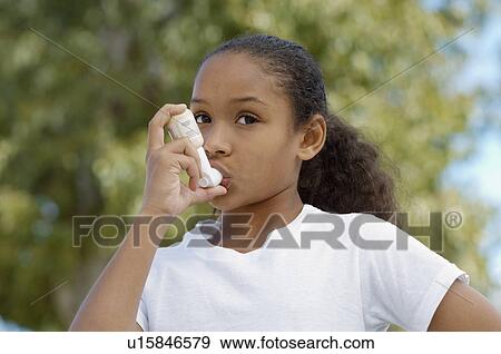 Stock Photo - Girl (7-9) using inhaler, outdoors. Fotosearch