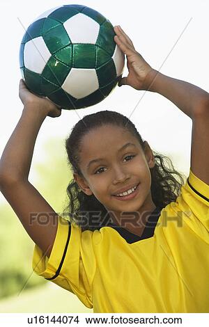 Girl (7-9 years) holding soccer ball above head, portrait View Large Photo Image Picture - Girl (7-9 years) holding soccer ball above head, portrait. Fotosearch
